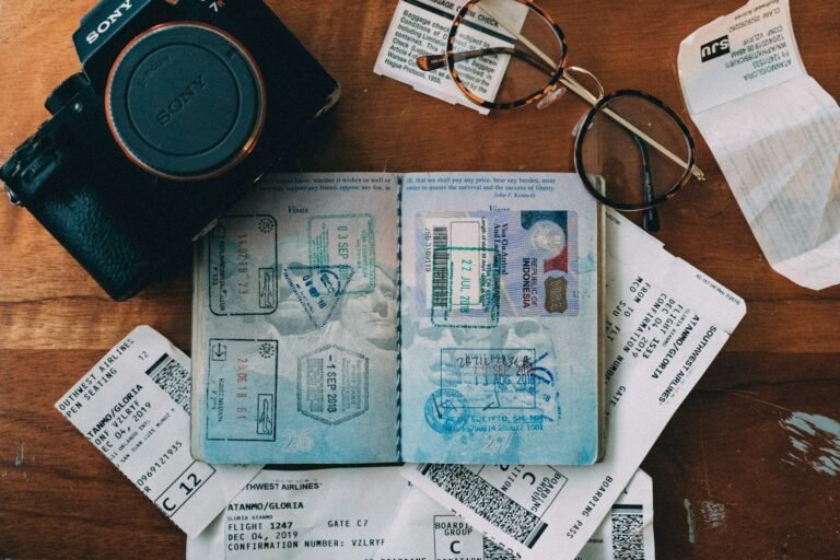 A passport open at its visa stamps on a desk with a camera